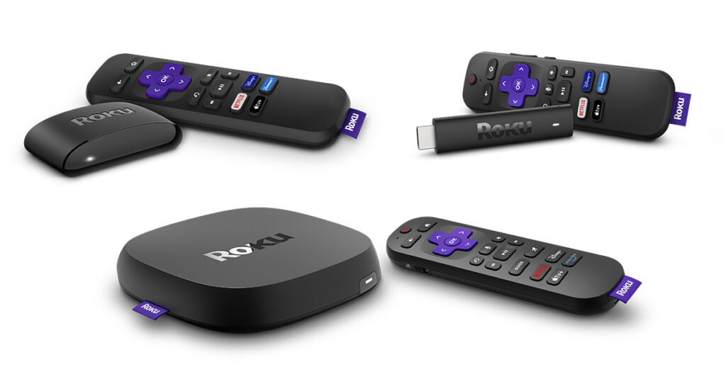 Various Roku streaming devices and their remotes displayed on a white background, including a Roku streaming stick, a small Roku box, and a larger Roku player, each paired with a black remote featuring purple directional buttons and dedicated streaming service keys.